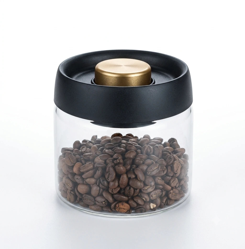 An airtight Crop borosilicate glass vacuum container filled with roasted coffee beans, featuring a sleek black lid and a gold vacuum pump button.