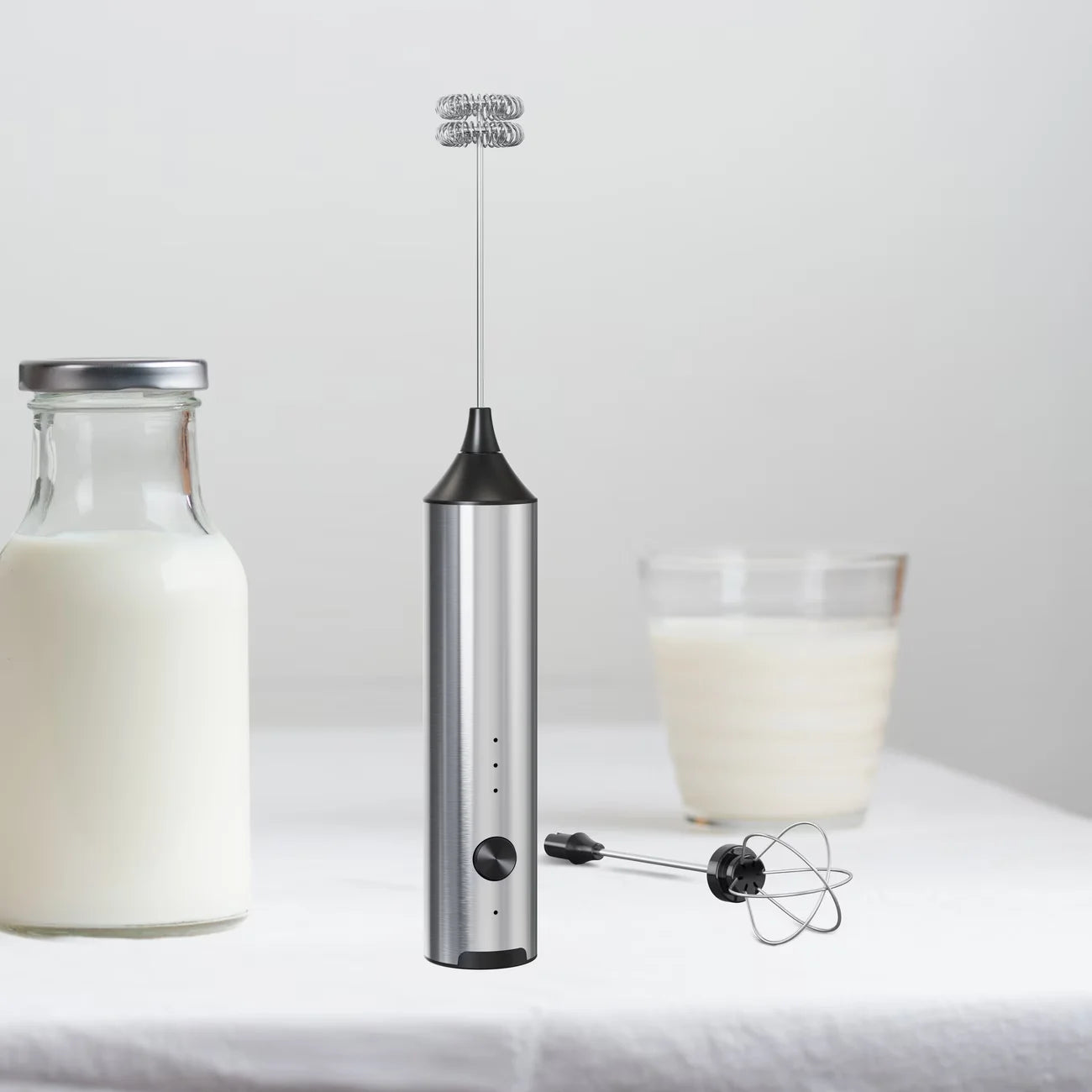 Crop Cafe electric milk frother wand resting on its sleek stainless steel countertop storage and charging stand.